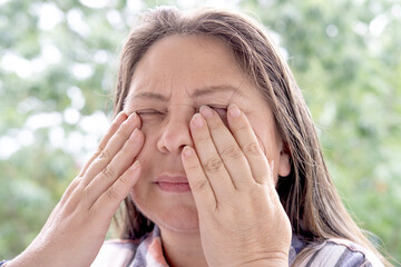 close-up of mature charismatic woman 50 years holding hand over eyes, eye pain treated medical...