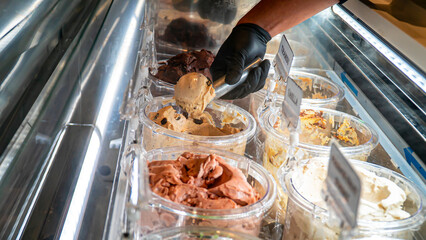 Barista scoops chocolate gelato in gelato display case