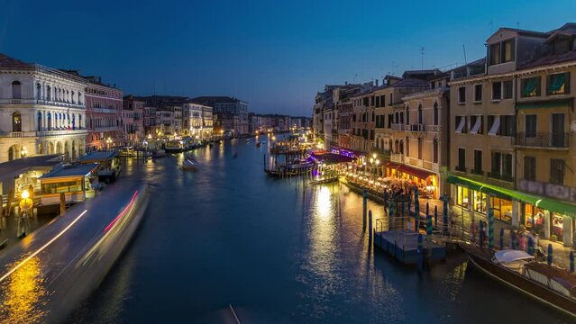 Grand Canal in Venice, Italy day to night transition timelapse. Panoramic view on gondolas and city lights from Rialto Bridge. Beautiful and romantic Italian city on water.