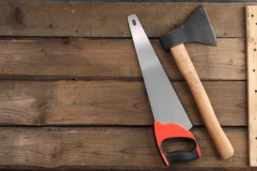 Tuinposter Saw with colorful handle and axe on wooden background, flat lay. Space for text © New Africa