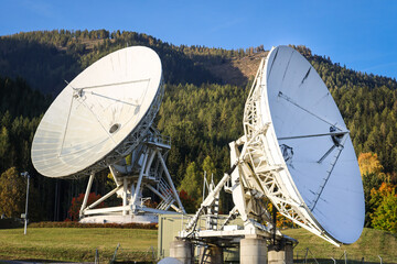 Satellite transmitter dishes pointing into the sky in beautiful forest landscape