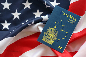 Canadian passport on United States national flag background close up. Tourism and diplomacy concept