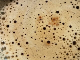 Texture, pattern, background with coffee with beige milk foam and bubbles of different sizes, prepared by a barista