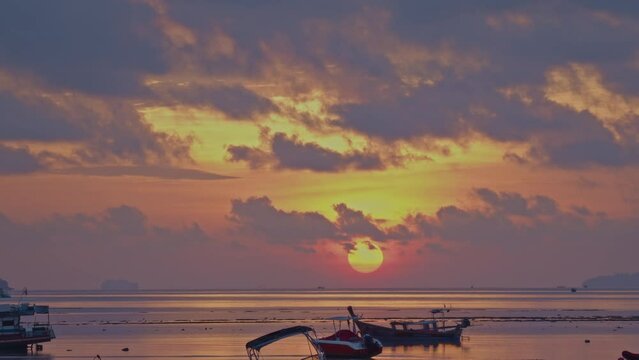 There was a big sun rising from the horizon as we watched it.
From the horizon, a large sun was rising into the sky.Clouds in a beautiful sky with fishing boats in the foreground in the morning.