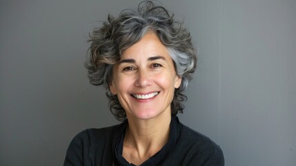 Fototapeta premium Smiling mature woman with curly grey hair, casual style.