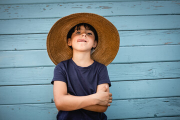 portrait of funny child in straw hat with folded arms - obrazy, fototapety, plakaty