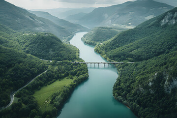 an aerial view of a river surrounded by mountains and greenery, with a bridge in the middle of the river and a bridge in the middle of the river.