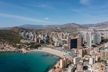 Fototapeta na wymiar Aerial drone photo of the town of Benidorm in Spain in the summer time showing the beach known locally as Playa de Finestrat and hotels and apartments around the small beach
