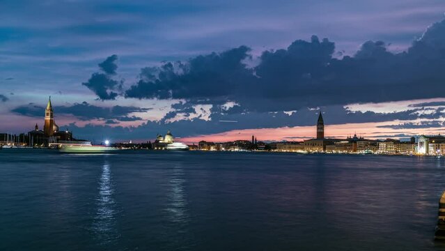 Basilica Santa Maria della Salute. San Giorgio Maggiore Island and San Marco square day to night transition timelapse, Venezia, Venice, Italy. Colorful cloudy sky. Evening illumination