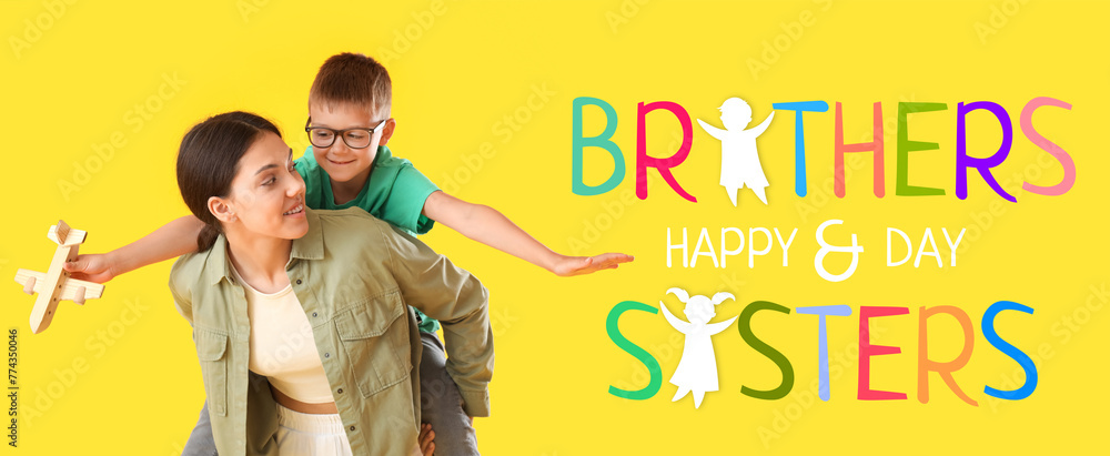 Wall mural Teenage girl carrying pickaback her little brother with wooden airplane on yellow background