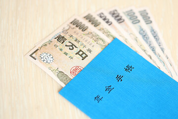 Japanese pension insurance book on table with yen money bills. Blue book for japan pensioners close up