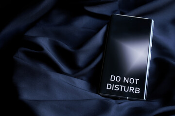 Modern smartphone with do not disturb inscription on the screen on a dark background of cosy...