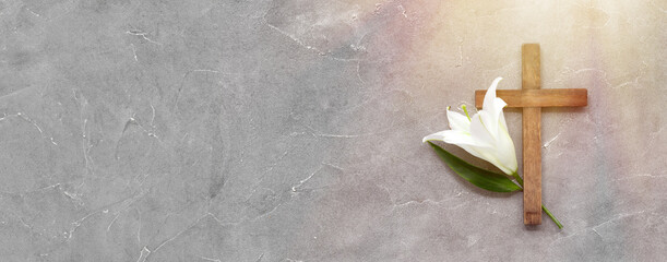 Wooden cross and lily on grey background with space for text, top view