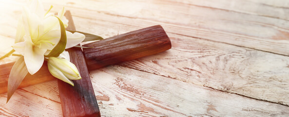 White lily and cross on wooden background with space for text, closeup