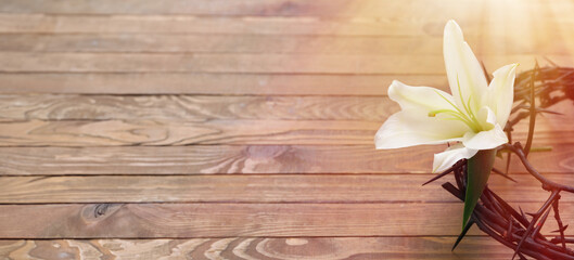 Crown of thorns and white lily on wooden background with space for text