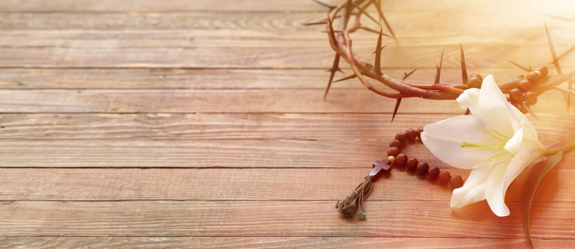 Crown of thorns, rosary beads and white lily on wooden background with space for text - Powered by Adobe