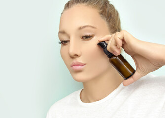 woman applying serum, lotion to her face