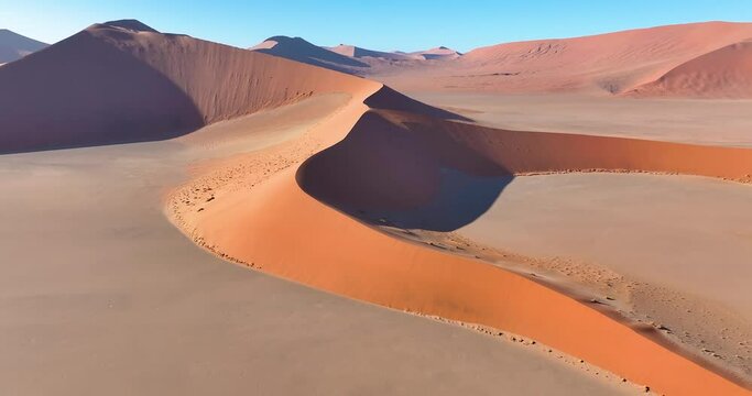 Drone flight over the glowing red sand dunes of the Namib Desert in Sossusvlei early in the morning