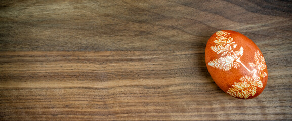 Decorated orange Easter egg on the wooden brown background - Concept of panoramic Easter  background with negative space