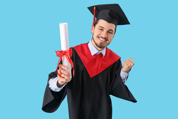 Cheerful male graduate student with diploma on blue background