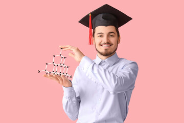 Male graduate student with molecular model on pink background