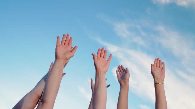 Individuals raise hands toward blue sky as sign of unity. Business collective decision making of people. People put hands up one by one. Hands are raised sequentially collective hand gestures teamwork