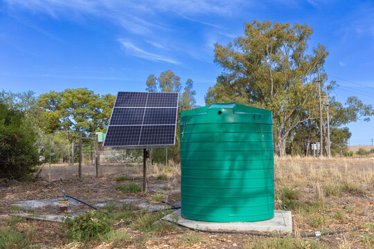 Large green plastic storage tank with solar panes connected to a borehole. Concept for extracting groundwater in locations where pumped water and electricity is not available.  