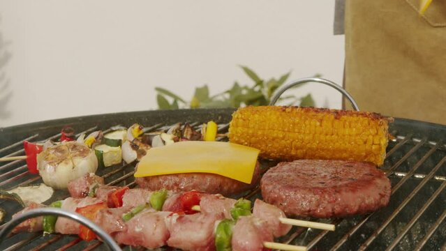 Cooking meat cutlets for humburgers, kebab and vegetables on grill close-up. Making chicken,beef or pork kebab. Barbecue for friends and family. Cafe and restaurant food.
