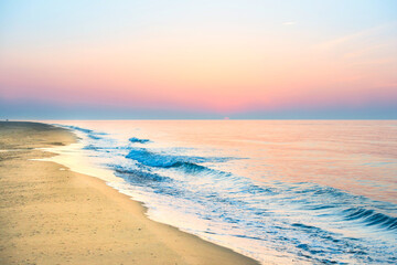 Sunset on beach with sea waves, coastline, sun and dramatic sky