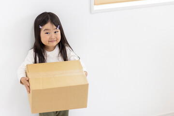 段ボール箱を持つ笑顔の女の子（3歳、日本人）