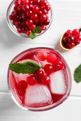 Tasty cranberry juice with ice cubes in glass and fresh berries on white wooden table, flat lay