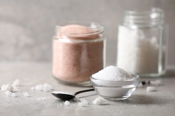 Different natural salt on grey table, closeup
