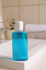 Fresh mouthwash in bottle on sink in bathroom, closeup