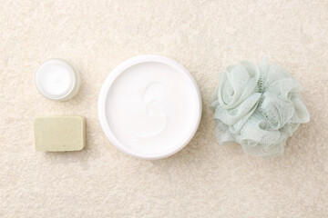 Fototapeta na wymiar Composition with body care cream in open jars and soap bar on light textured table, flat lay