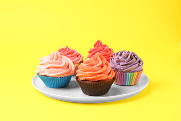 Delicious cupcakes with bright cream on yellow background