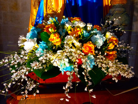 Addobbi floreali ai piedi della statua raffigurante la Madonna