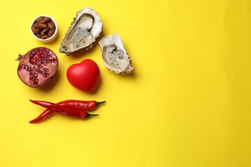 Natural aphrodisiac. Different food products and red decorative heart on yellow background, flat...