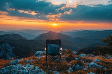 Serene mountain landscape with a single folding chair overlooking a sunset