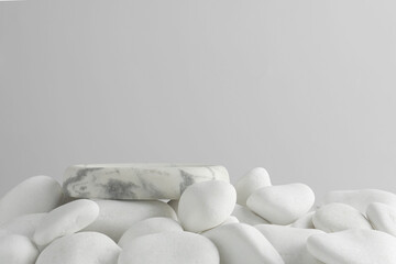 Presentation for product. Stone podium and white pebbles on light background. Space for text