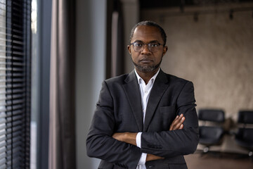 Professional middle-aged businessman with glasses standing confidently with arms crossed in a...