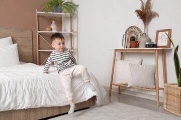 Little boy on bed in bedroom. Child at risk