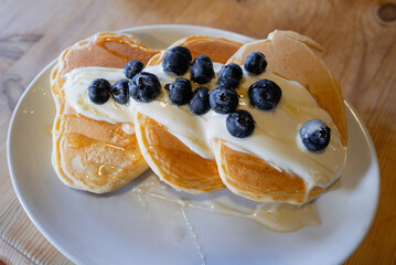 Shallow focus on blueberries drizzled with honey on a creamy yoghurt on top of three thick pancakes