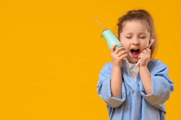 Cute little dentist with oral irrigator and toothbrush on yellow background