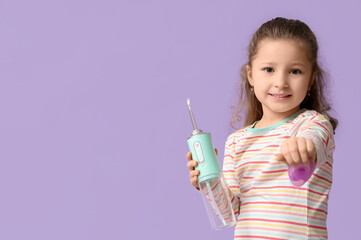Cute little girl with oral irrigator and dental floss on lilac background