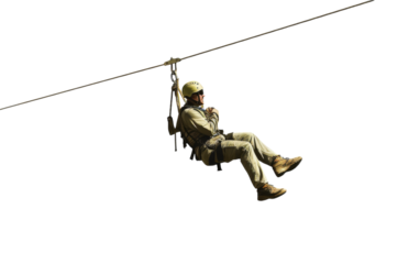 A soldier hangs from a rope, navigating a zip line across a thrilling terrain