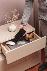 Woman putting her phone in drawer with different gadgets at home