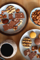 Cup of tea or coffee, cookies, macaroons, chocolate, various nuts and cocoa powder on wooden table. Top view.