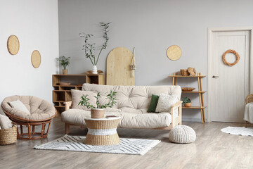 Stylish interior of light living room with bamboo stems on coffee table, armchair and white sofa - obrazy, fototapety, plakaty