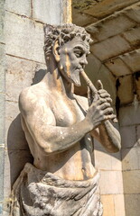 An ancient statue depicting the ancient deity Fawn (Satyr) playing the flute © allegro60