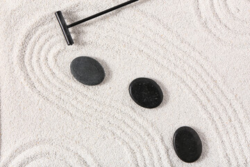 Rake and stones on sand with lines in Japanese rock garden. Zen concept